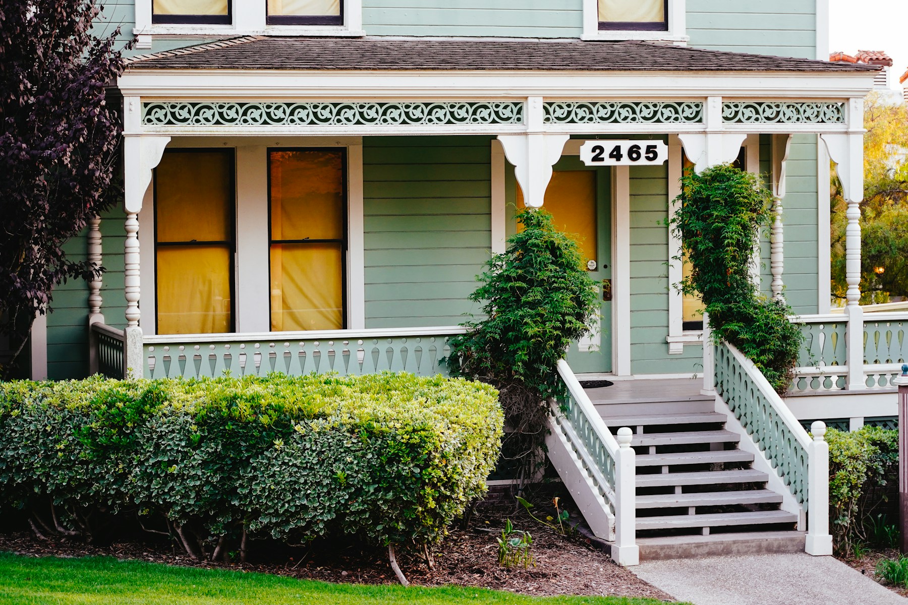 Historic San Diego Victorian home with detailed wraparound porch and manicured hedges